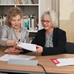 deux femmes s'échangent des documents